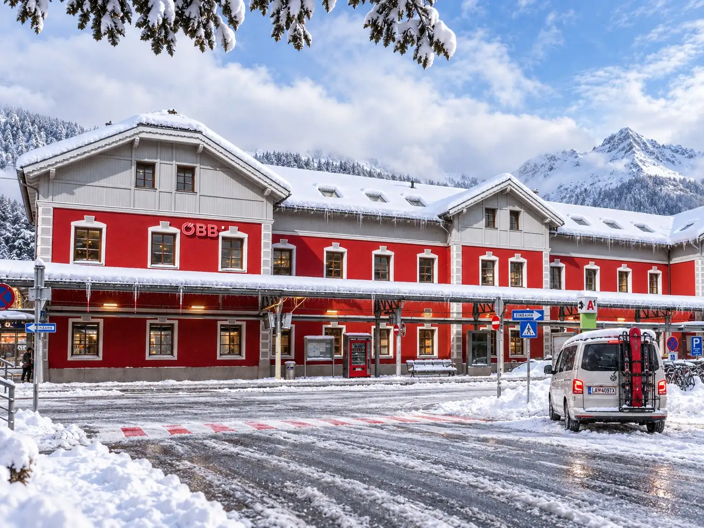 Taxi St. Anton to Bludenz – pickup and drop-off at Bludenz railway station Taxi St. Anton to Bludenz: Taxi Anton 4×4 minibus with skis on the rear rack in front of the red ÖBB railway station Bludenz in winter